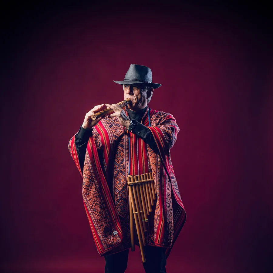 Integrante de Conjunto Calichal tocando zampoña, con poncho andino.